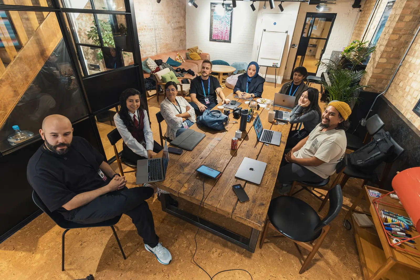 A growth team gathered around a large wooden table with laptops during a workshop