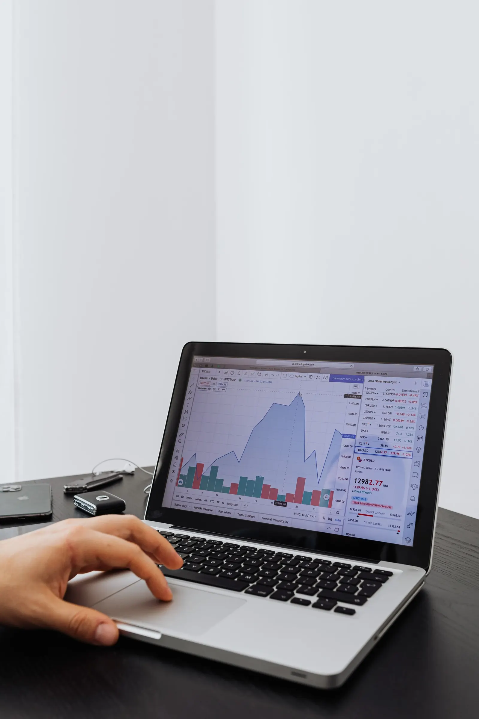 Laptop screen showing a rising line chart with bar graphs in a bright workspace