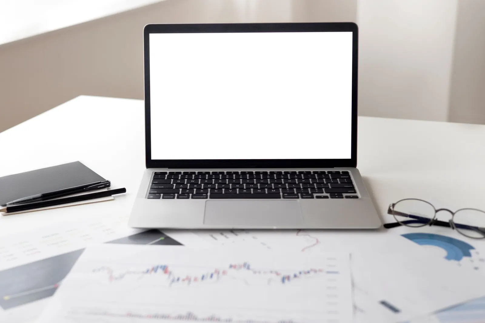 Open laptop on a clean white desk next to notes, ready for drafting onboarding emails