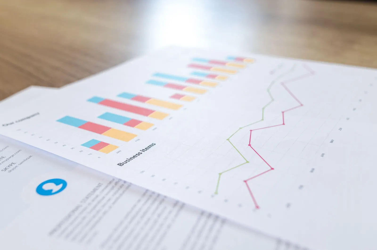 Printed sheets with colorful bar charts and line graphs laid on a wooden desk