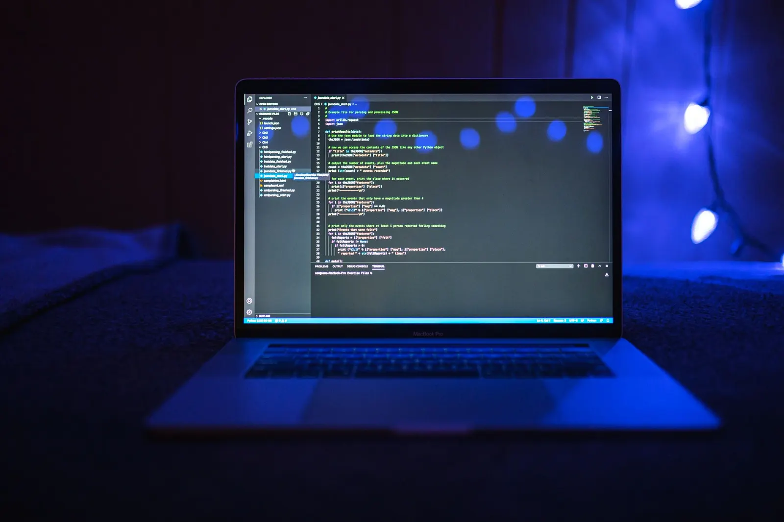 Laptop with code on screen glowing under blue light in a dark room