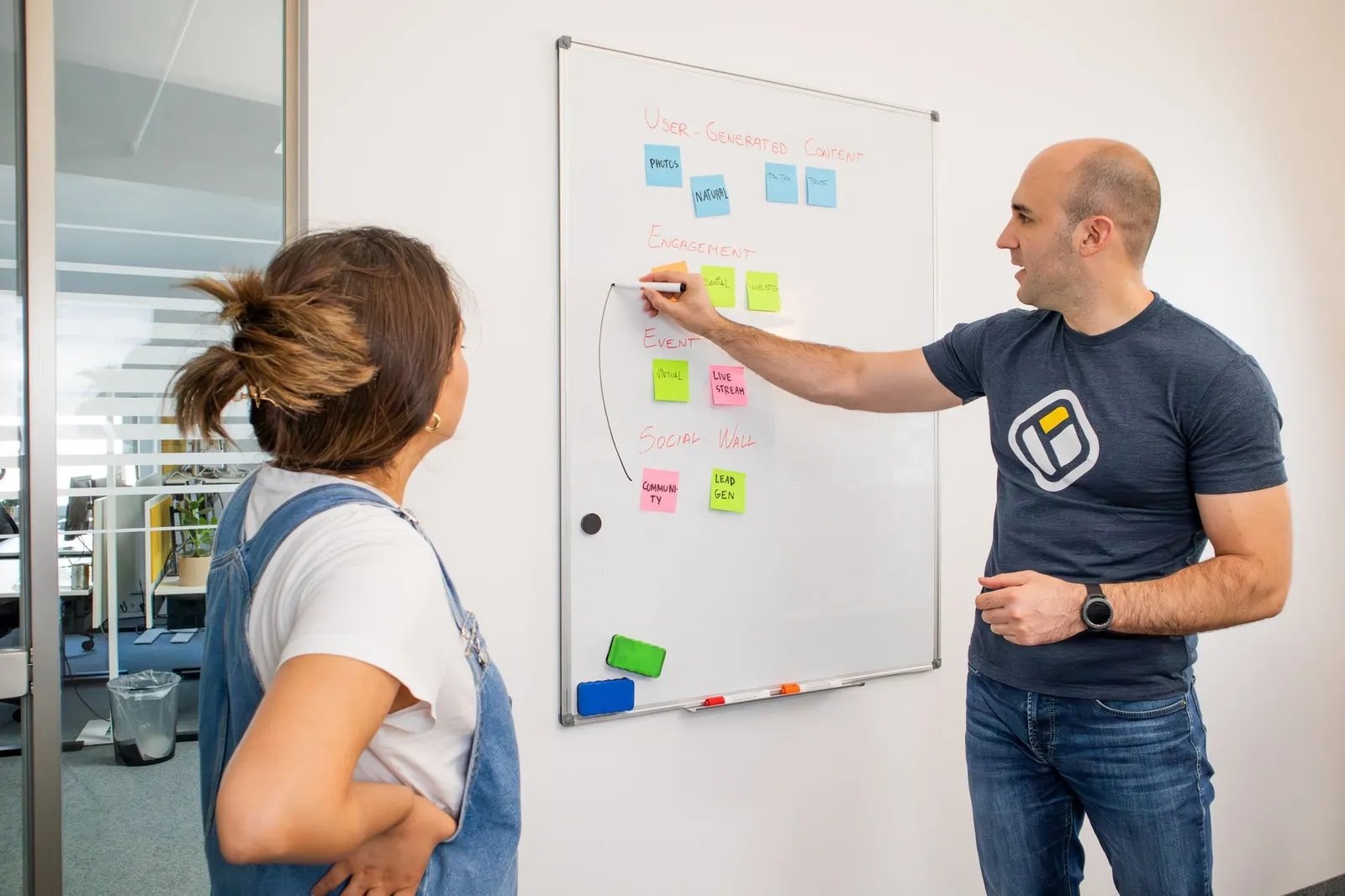 Two colleagues mapping a process with colorful sticky notes on an office whiteboard