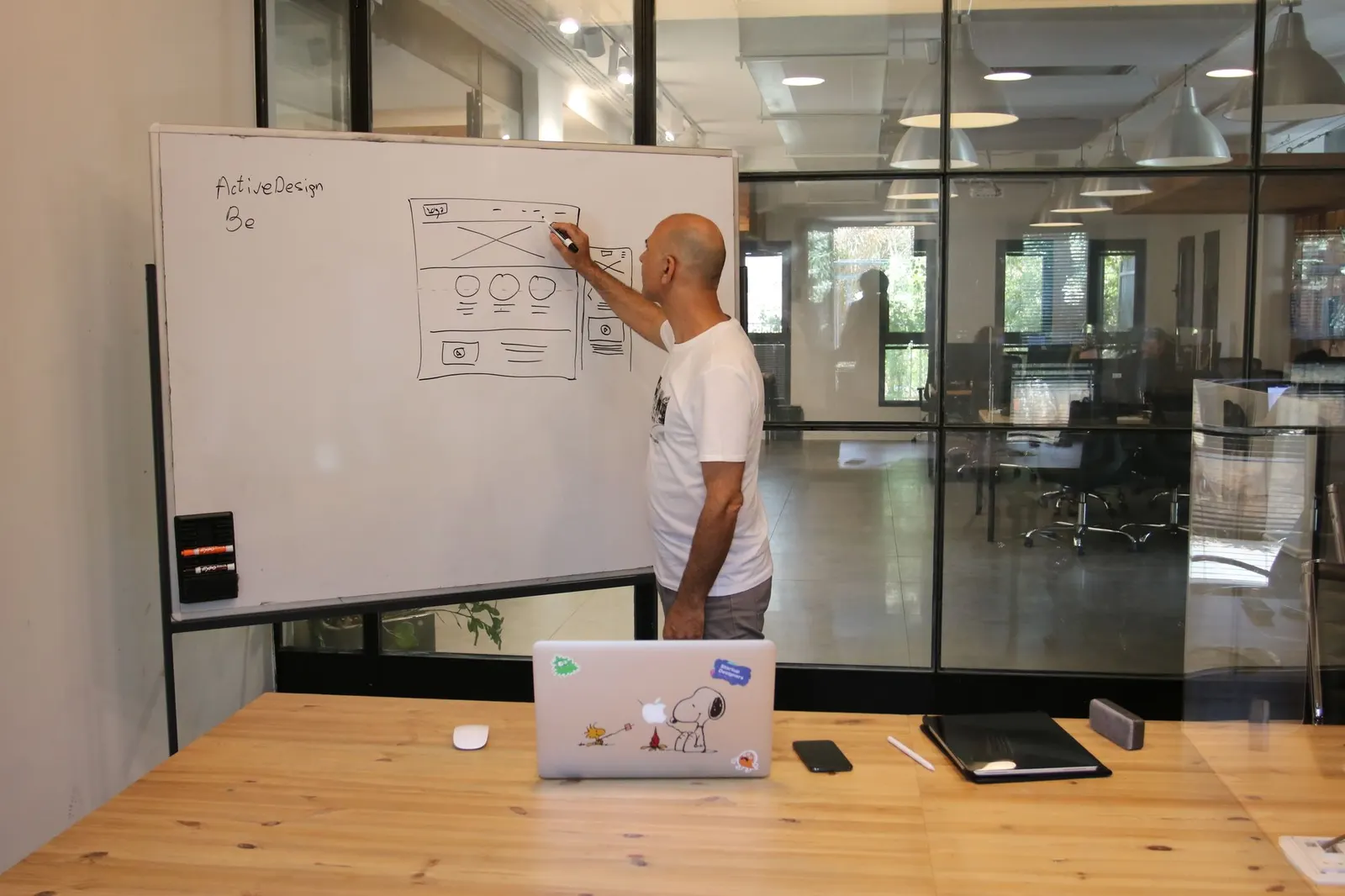 Designer sketching a user interface wireframe on an office whiteboard
